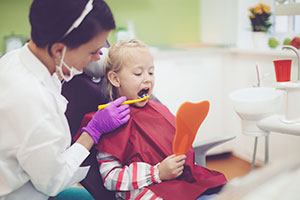 Dentist examining young dental patient during children's dentistry visit