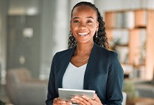 Woman smiling while holding tablet in office