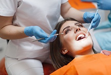 Patient reclining in dental chair, getting her teeth examined