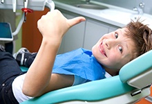 Young boy giving thumbs up for dental treatment
