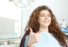 Woman in the dental chair giving a thumbs-up after dental bonding treatment