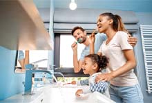 Family preventing dental emergencies in Crookston by brushing their teeth