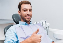 Bearded man giving a thumbs up in dental chair