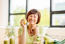 Woman with dental implant replacement teeth holding an apple