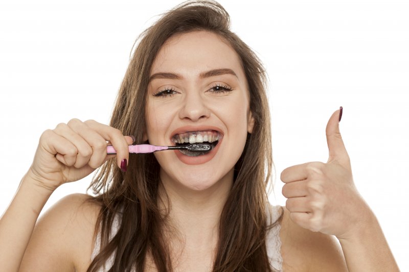 a woman using charcoal to brush her teeth