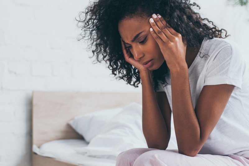 Woman experiencing TMJ headache at home