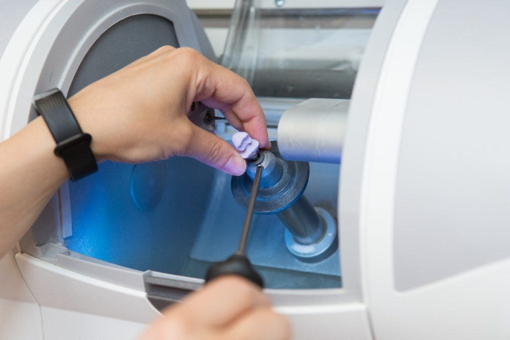 Dentist using a CEREC machine to make a dental crown.