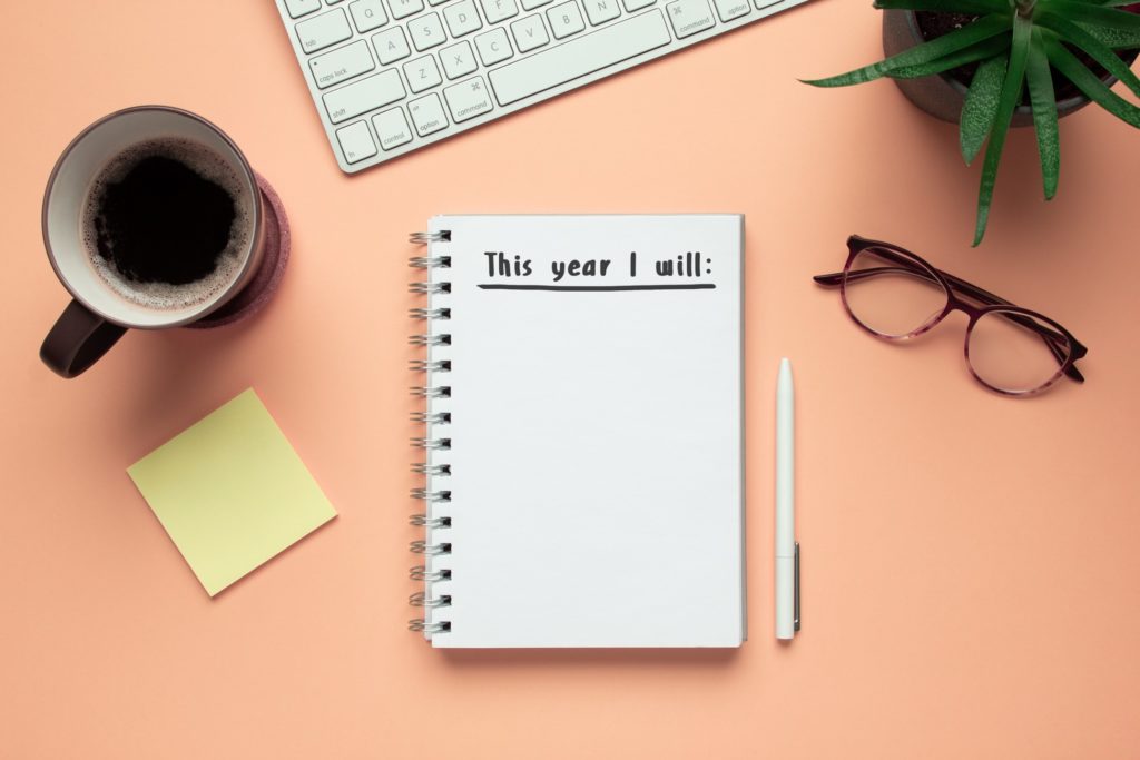 Notepad, cup of coffee, glasses, and pen on desk