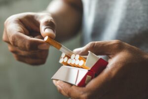 Person pulling cigarette from pack.